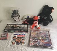 Photo of the entire collection spread out showing signed plaque, plush bears, diecast car, DVD, and trading card.