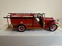 Side view showing detailed ladders, hoses, accessories, and red metal body of the vintage fire truck model.
