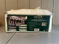 Box front showing brand Polymer Products LLC Outdoor String Light Set with product features, including 6 globe lights, weather-resistant coating, and polyethylene housing.