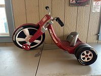 Full side view of the red Radio Flyer Big Flyer tricycle showing the front and rear wheels, frame, pedals, seat, and handlebars.