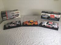 Front view of the three die-cast cars with their boxes and display cases showing Kevin Harvick branding and sponsor decals.