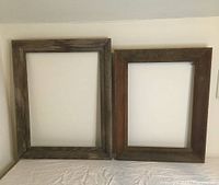 Two rectangular antique wooden frames displayed side by side on a white background, showing differences in wood tone and wear.