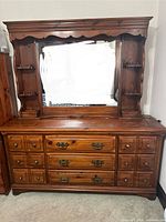 Full front view of the solid wood dresser with mirror and built-in lights. Shows detailed drawer hardware and shelving on sides of mirror.