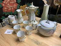 Full lot arrangement showing teapot, six tea cups, and three additional ceramic pitchers and vases on wooden table