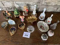 Photo showing all 15 knick-knacks assorted porcelain figurines, bells, trinket boxes, and small dishes on wood surface