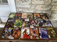 18 vintage comic books arranged on a wooden surface, showing a variety of titles including Drax, Green Arrow, and others.