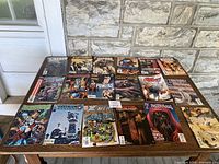 Full view of all 18 comic books laid out on a table showing front covers including Swamp Thing, Wolverine, and others.
