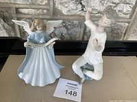 Front view of two porcelain figurines: a blue robed angel and a girl brushing hair.