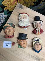 Six Bossons chalkware heads displayed on a wooden surface, showing full frontal views including Santa Claus and other character heads.
