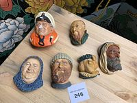 Top down view of all six chalkware heads arranged on wooden surface showing variety of characters.