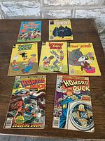 Seven vintage comic books arranged on a wooden surface featuring varied colorful cartoon covers.