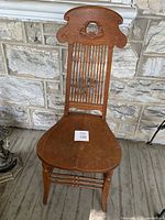 Full front view of the antique wooden chair showing the seat, legs, and backrest design.