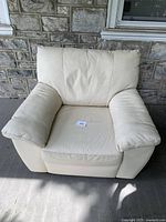 Front view of the off-white leather Vreta lounge chair showing padded armrests and cushion seat.