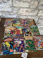 Photo of 12 vintage Marvel comic books dated from the 1970s and 1980s, including multiple Fantastic Four issues, Thor, What If? Thor vs Conan, Batman Detective, and others.
