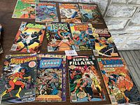Top view of 12 vintage comic books arranged on a surface showing colorful covers of Marvel and DC titles