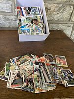 Image showing a white box filled with mixed sports trading cards, predominantly baseball with some football and basketball cards visible.