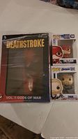 Photo showing the front of the Deathstroke Vol 1 Gods of War book and mask set alongside boxed Funko Pop figures of The Flash and Thor from Marvel Avengers Endgame.