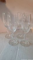 Four clear crystal champagne flute glasses with vertical cut pattern on the bowl, displayed on a flat surface.