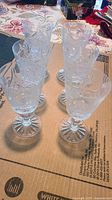 Set of six Ajka crystal claret wine glasses arranged in two rows, showing pinwheel etched pattern on bowls and starburst bases.