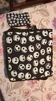 Top view of black messenger bag and small pouch laid flat, showing Jack Skellington face pattern