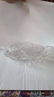 Side profile view of a vintage American cut glass celery tray placed on a white background showing intricate floral and geometric cut glass design and scalloped edges.