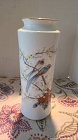 Front view of porcelain vase showing hand-painted birds and blossoms design with gold rim.