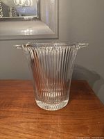 Front angle view of clear ribbed glass ice bucket or vase with handles