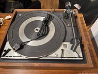 Full top view of the Dual 1215 turntable showing the platter, tonearm, and power cord on the wooden base.