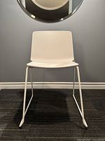 Front view of the white Kristalia Rama chair showing the molded plastic seat and steel sled base.