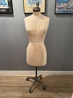 Full view of the dress form showing fabric-covered mannequin torso on metal pole and cast iron base with wheels.