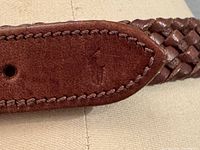 Close-up of the leather tip showing embossed Ralph Lauren Polo logo and braided detail.