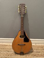 Full view of the entire vintage Winston mandolin displaying its teardrop shape, eight tuning keys, and natural wood finish.