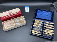 Carvel Hall steak cutlery in original box beside 12-piece fish knife and fork set in blue satin presentation box