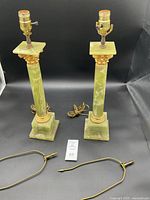 Full view of the matching pair of Empire style green onyx column lamps on black background showing cord and place markers.