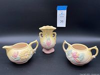 Photo showing the cream pitcher, sugar bowl, and flower vase from front angle against black background with lot tag.