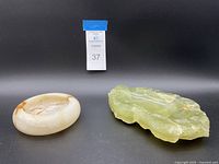 Photo of round marble bowl with beige and brown swirls next to irregular jade ashtray with translucent light green color.