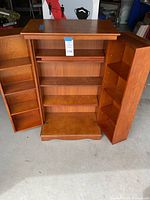 Interior view of open cabinet doors revealing multiple shelves on doors and central compartment for media storage.