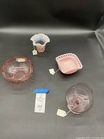 Wide shot of four pink glass items - bon bon dish, vase, bowl, and snifter