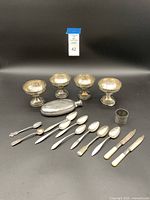 Five ice cream cups arranged in an arc with the flask and various flatware arranged in front on black backdrop.