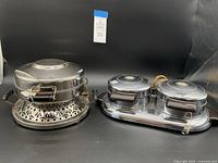 Photo of two vintage electric waffle makers side by side on a black surface, left is single waffle maker with decorative base and right is double compartment waffle maker.