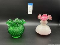 Two Fenton glass vases: green hobnail textured vase with ruffled edge and pink and white opalescent vase with ruffled pink top edge.