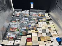 View of entire lot consisting of multiple plastic bags and paper envelopes containing vintage matchbooks arranged on a flat surface.
