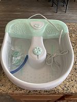 Conair foot spa base unit on kitchen counter with attached power cord and control dial visible