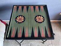 Top view showing the backgammon board design painted on the foldable tabletop with clear star-shaped center pieces and triangular points in red, green, and black colors.