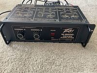 Front view of Peavey M-2600 power amplifier with channel controls, power indicator LED, and brand labeling.