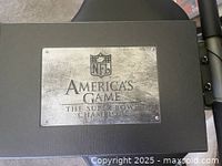Metal box top with NFL logo and America's Game The Super Bowl Champions engraved on a metal plate.