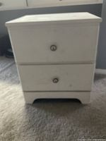 Front view of the white chest of drawers showing 2 drawers and the bottom open shelf space.