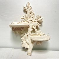 Front view of the chalkware trinket shelf showing detailed tree branch design with leaves and pinecones along with two oval shelves.