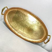 Top and angled view of the hammered brass serving tray with handles showing the shiny interior surface and patina around the edges.
