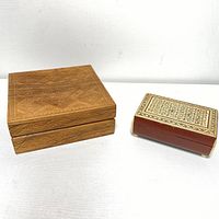 Two carved and inlaid wood boxes: larger solid wood box with geometric carvings, smaller polished wooden box with detailed marquetry inlay and metal accents.
